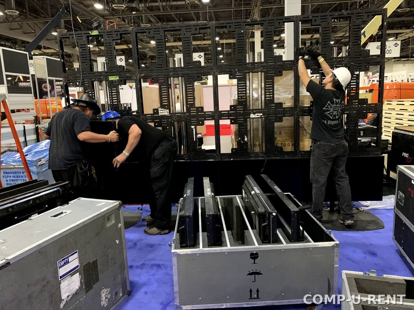 Crew assembling a large video wall on the show floor